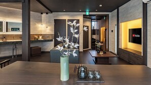 Un hall d’hôtel moderne avec un comptoir d’accueil, un grand vase orné de branches, une cafetière et des verres disposés sur un plateau.