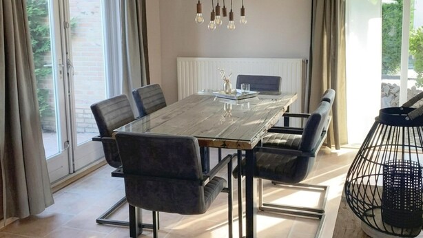 A dining area with a table, chairs, a chandelier, and curtains. - Spacious Stay Near the Sea (Breskens)