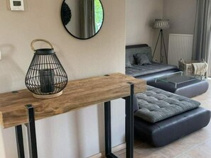 A modern living room with a wooden console table, a black wireframe lamp, a grey sofa, and a floor lamp. - Spacious Stay Near the Sea (Breskens)