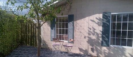 A house with a brick exterior, a tree in the front yard, and a gravel pathway leading to the entrance.