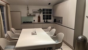 Une cuisine moderne équipée d’une table à manger, de chaises, d’une cuisinière et d’une poubelle.