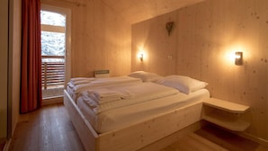 A wooden room with a bed, a nightstand, and a window with curtains. - Lavish Chalet With Finnish Sauna (Stadl-Predlitz)