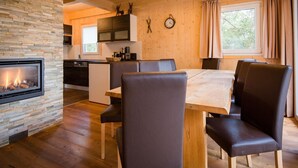 A cozy cabin interior with a stone fireplace, wooden dining table, and chairs. - Lavish Chalet With Finnish Sauna (Stadl-Predlitz)