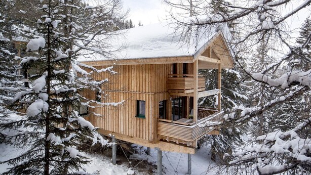 A wooden cabin with a balcony, surrounded by snow-covered trees. - Lavish Chalet With Finnish Sauna (Stadl-Predlitz)