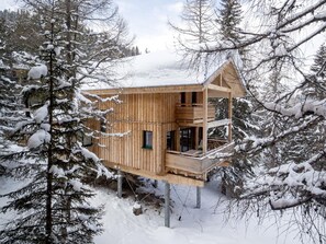 A wooden cabin with a balcony, surrounded by snow-covered trees. - Lavish Chalet With Finnish Sauna (Stadl-Predlitz)