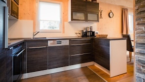 A modern kitchen with dark wood cabinets, a built-in dishwasher, and a stone backsplash. - Lavish Chalet With Finnish Sauna (Stadl-Predlitz)