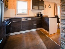 Una cocina moderna con armarios de madera oscura, lavavajillas integrado y un salpicadero de piedra.
