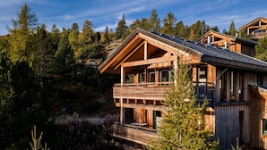 Une cabane en bois dotée d’un balcon, entourée d’une forêt dense.