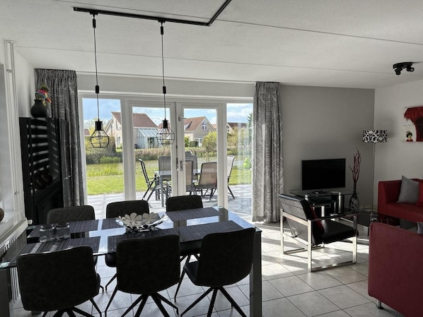 A modern living room with a dining area, a TV, and a red sofa. - Bungalow in Breskens Near Beach & Lighthouse (Breskens)