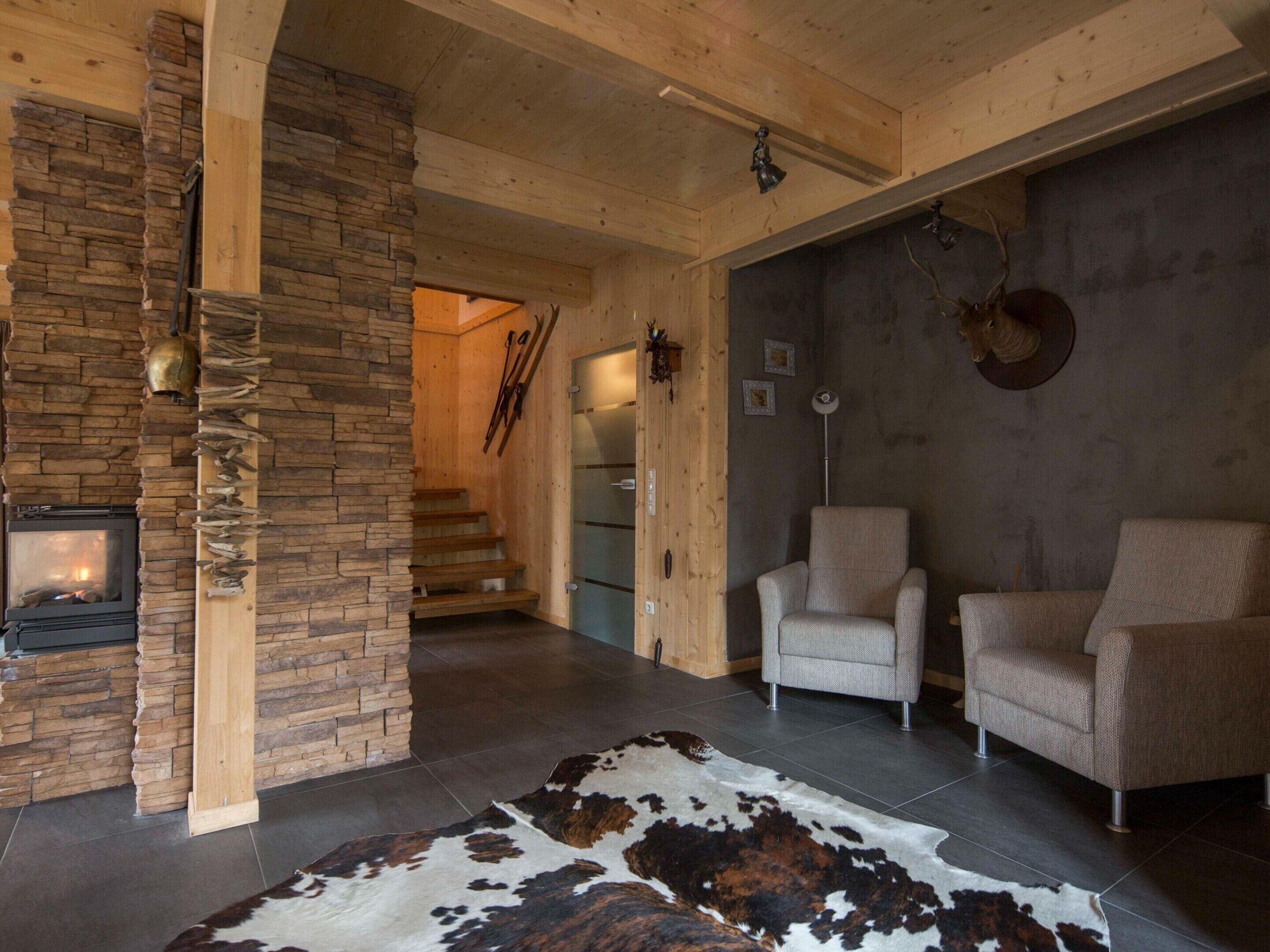 A cozy living room with a stone fireplace, a cowhide rug, and two armchairs.