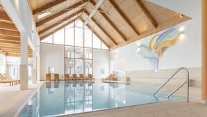 An indoor swimming pool with clear glass walls, wooden beams, and a tiled floor. - Apartment for up to 6 People (Sankt Georgen am Kreischberg)
