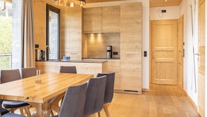 A modern kitchen with wooden cabinets, a large island, and a dining area with a wooden table and chairs.