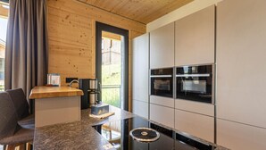 A modern kitchen with a built-in oven, a coffee machine, and a granite countertop.