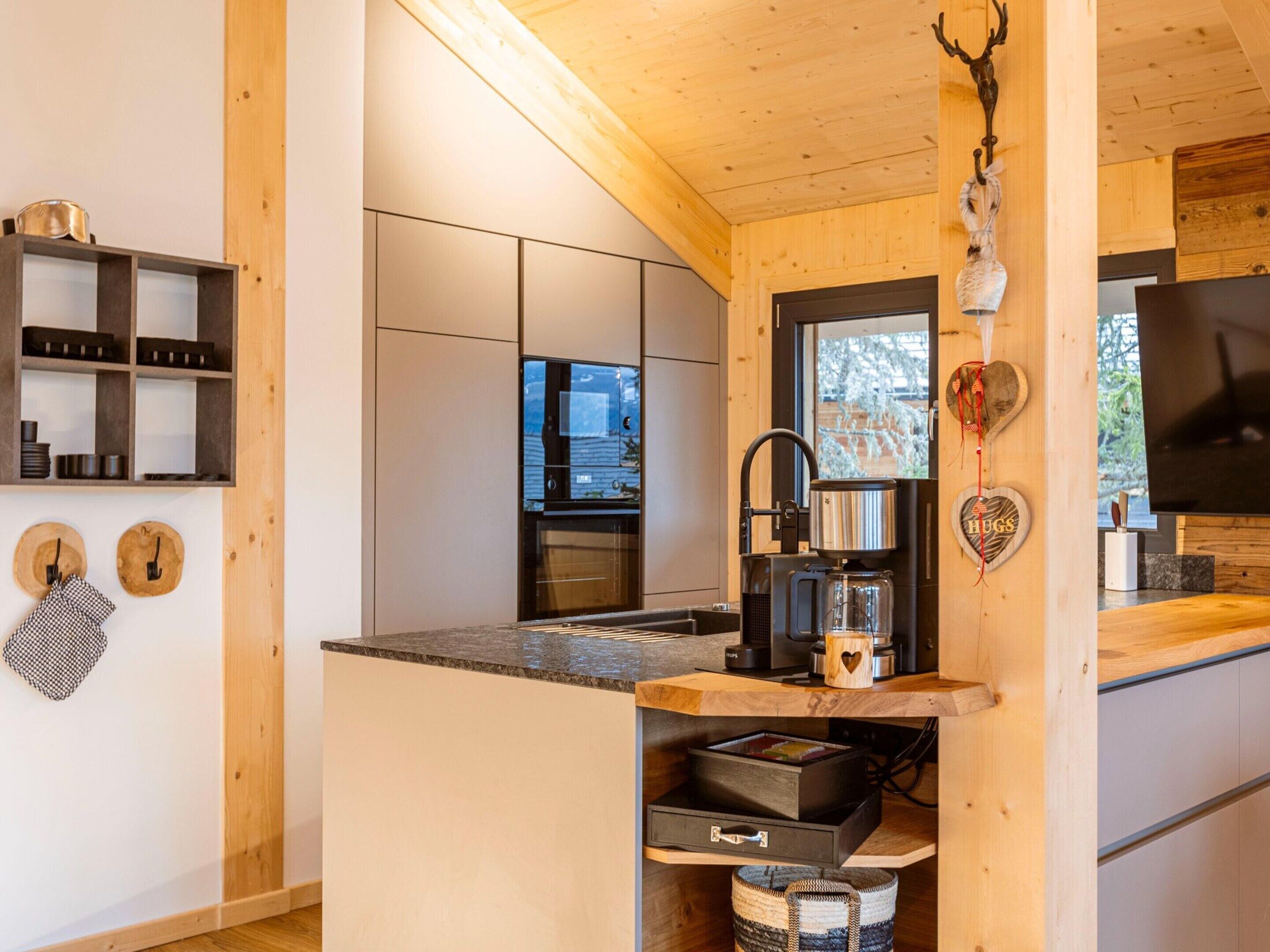 Una cocina moderna con armarios de madera, horno empotrado y cafetera.