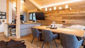 A modern kitchen with wooden accents, a dining area with grey chairs, and a cozy seating area with a fluffy white throw.