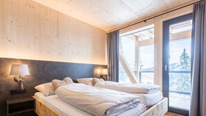 A wooden bed in a room with a large window and a view of a snowy landscape.