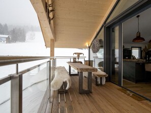 A wooden deck with a bench and a table, overlooking a snowy landscape. - Lovely Chalet With Sauna (Schladming)