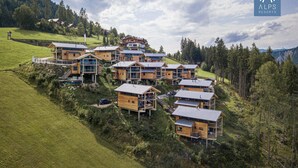 Un conjunto de cabañas de madera de varios pisos, ubicadas en una ladera con un bosque de fondo.