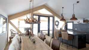 Un comedor amplio con una mesa y sillas de madera, una cocina con barra, y un ventanal que deja entrar luz natural.