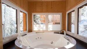 A modern bathroom with a large freestanding bathtub, wooden walls, and large windows offering views of a snowy landscape. - Chalet in Turracherhohe With Sauna & Ski Access (Stadl-Predlitz)