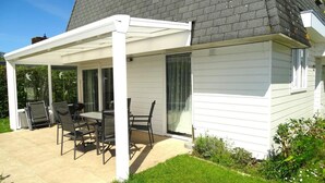 A covered patio with a table and chairs, a white exterior wall, and a dark roof. - Holiday Home Breskens Near Scenic Beaches (Breskens)