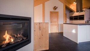 A modern kitchen with a built-in fireplace, wooden cabinets, and a large island. - Premium Chalet With Infrared Sauna (Stadl-Predlitz)