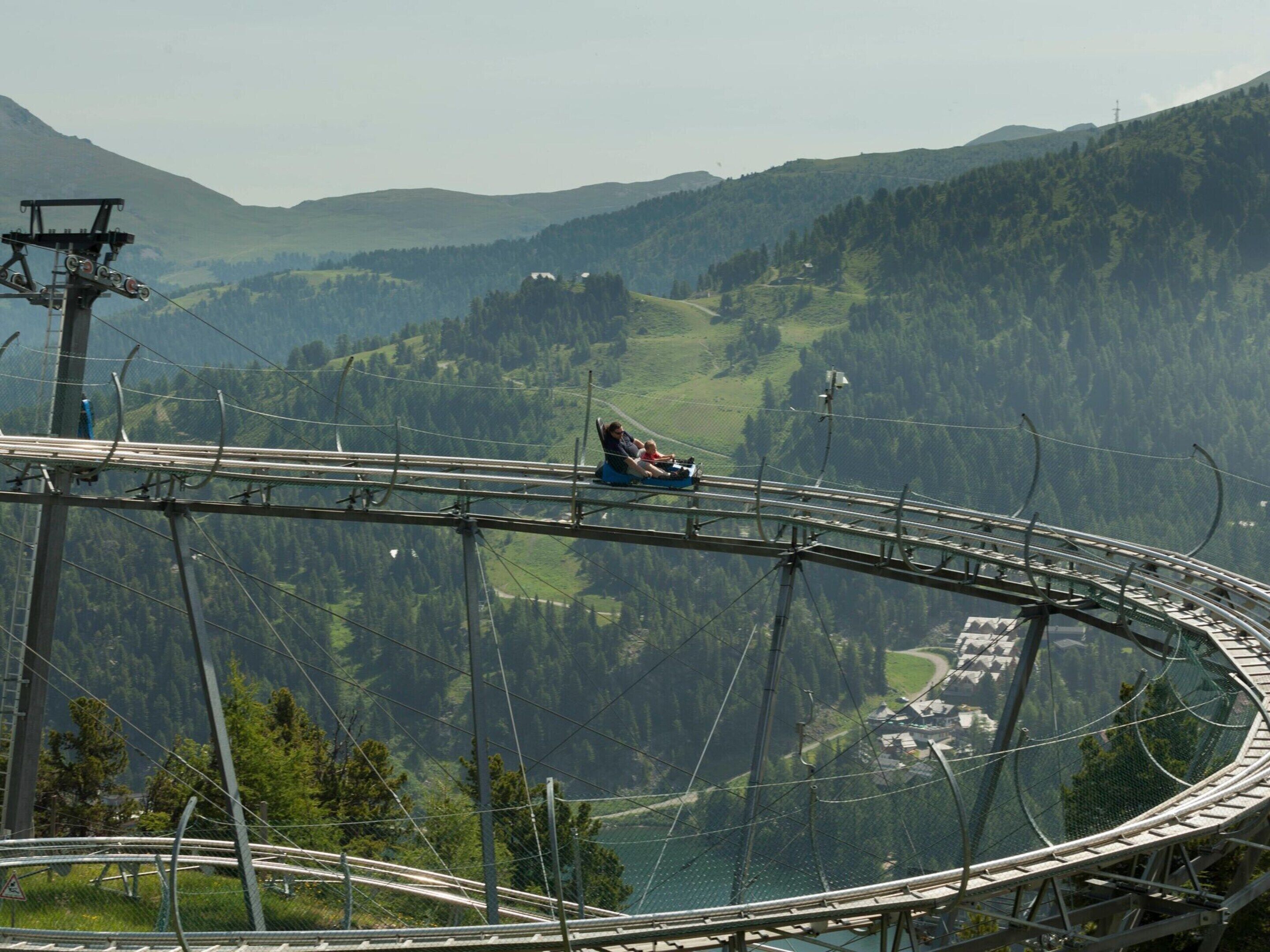 Un telesilla con una persona sentada, recorriendo un sistema de cables sobre un paisaje montañoso.