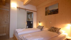 A double bed with white linens and pillows, wooden headboard, and a painting on the wall. - Premium Chalet With Infrared Sauna (Stadl-Predlitz)
