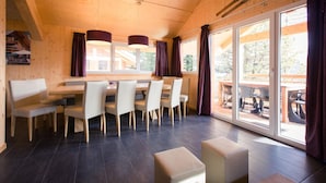 A wooden interior with a dining area, large windows, and a view of the outdoors. - Premium Chalet With Infrared Sauna (Stadl-Predlitz)