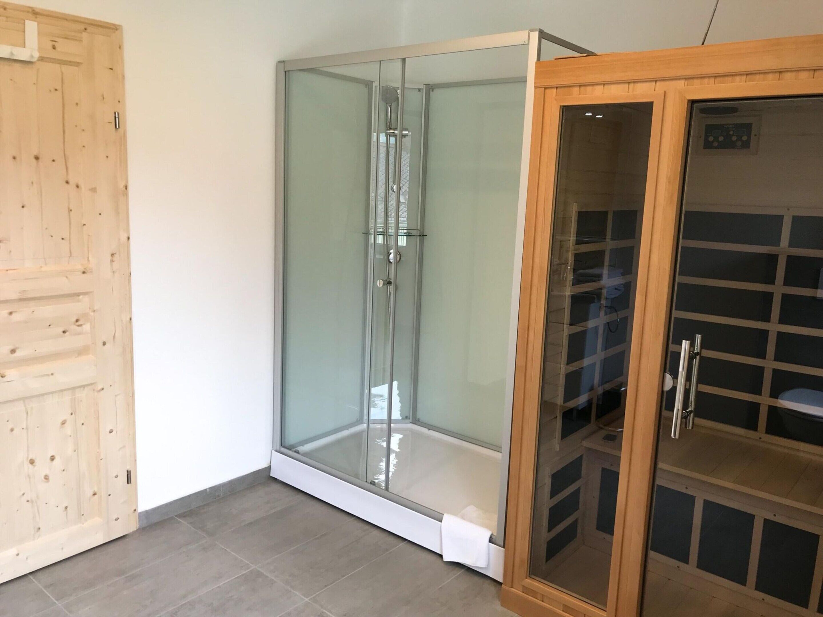 A room with a glass-enclosed shower, a wooden door, and a cabinet with a grid pattern.