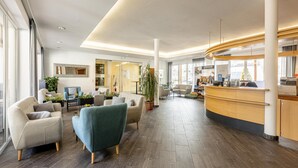 Un hall d’entrée spacieux avec un comptoir de réception, un espace salon et de grandes fenêtres.