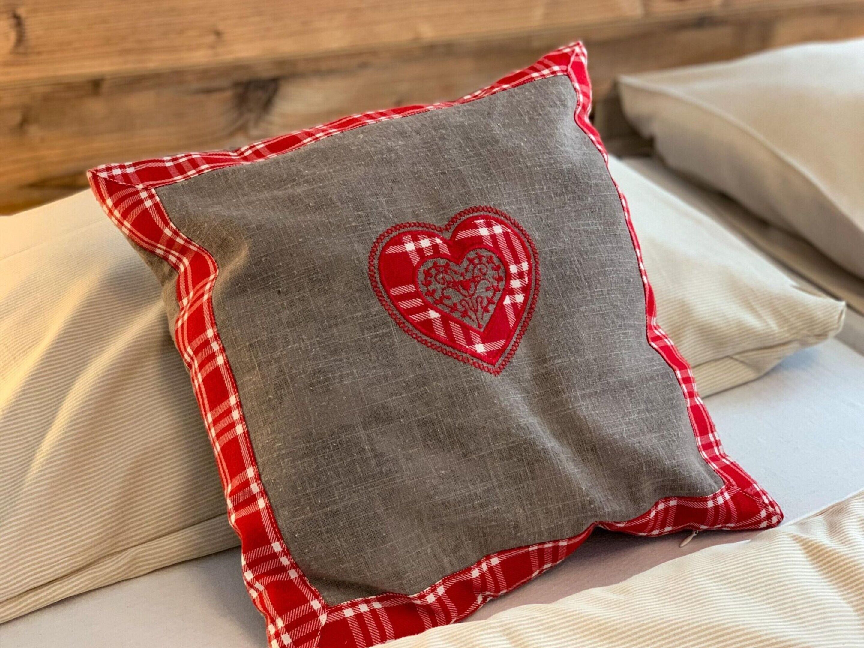 A pillow with a heart design on a bed.