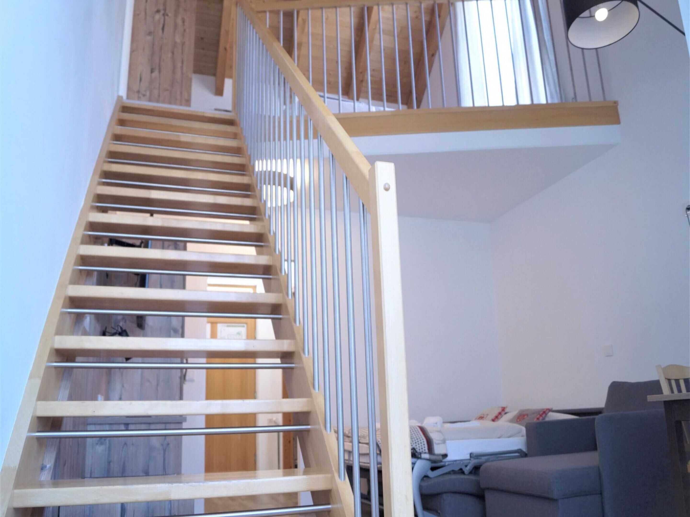 Una escalera de madera con barandales de metal que sube a una zona elevada.