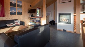 Ein gemütliches Wohnzimmer mit Kamin, Holzwänden und einer Bücherwand.