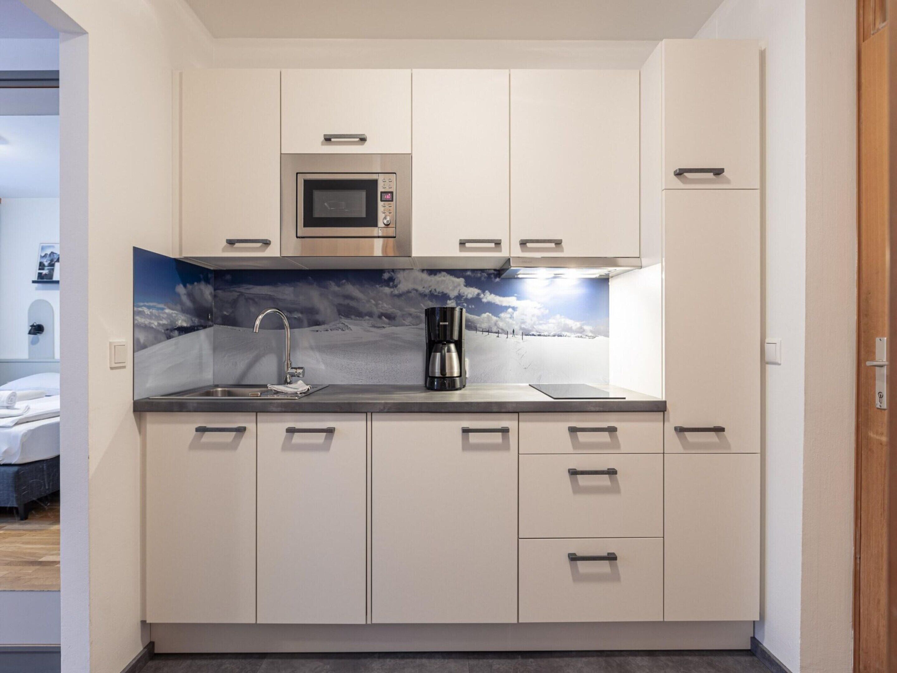 A compact kitchen with a microwave, coffee maker, and a sink.