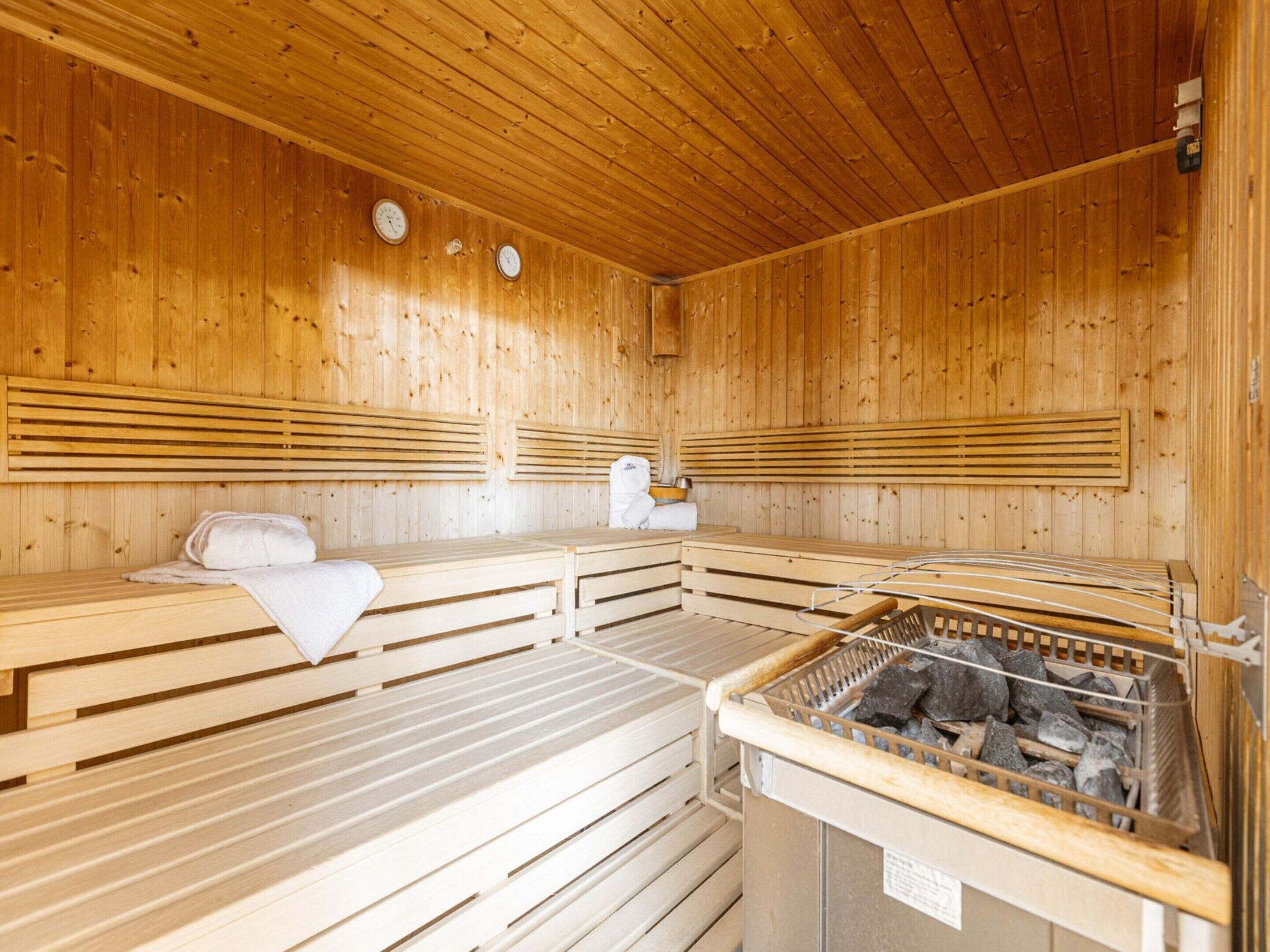 A sauna room with wooden benches and a stone heating element.
