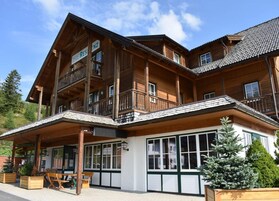 Una cabaña de madera con varios balcones, ventanas amplias y mobiliario exterior.