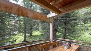 A wooden deck with a table and benches overlooking a forested area. - Cozy Chalet With hot tub (Stadl-Predlitz)