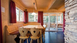 A wooden cabin interior with a large dining table, wooden chairs, a bench, and a stone wall. - Cozy Chalet With hot tub (Stadl-Predlitz)