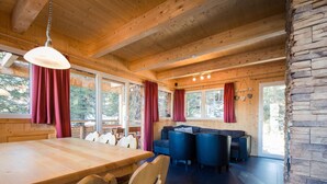 A wooden interior with a dining table, chairs, a sofa, and a stone accent wall. - Cozy Chalet With hot tub (Stadl-Predlitz)