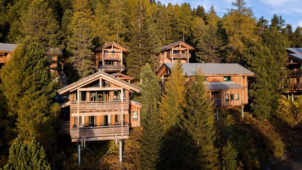 A wooden cabin complex with multiple levels, surrounded by dense forest. - Cozy Chalet With hot tub (Stadl-Predlitz)