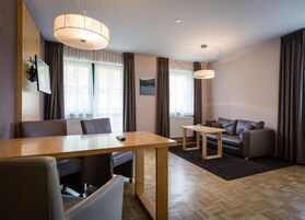 Una sala moderna con una mesa de comedor de madera, un sofá y dos l ámparas colgantes.