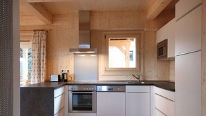 Eine moderne Küche mit Holdekor, einer zentralen Kochinsel, Edelstahlgeräten und einem Fenster für natürliches Licht.