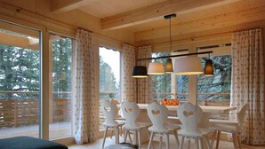 Ein Holzinterieur mit Essbereich, großen Fenstern und Blick auf Bäume.