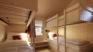 Ein Schlafzimmer einer Holzhütte mit Etagenbetten, einem Fenster und einem Schreibtisch.