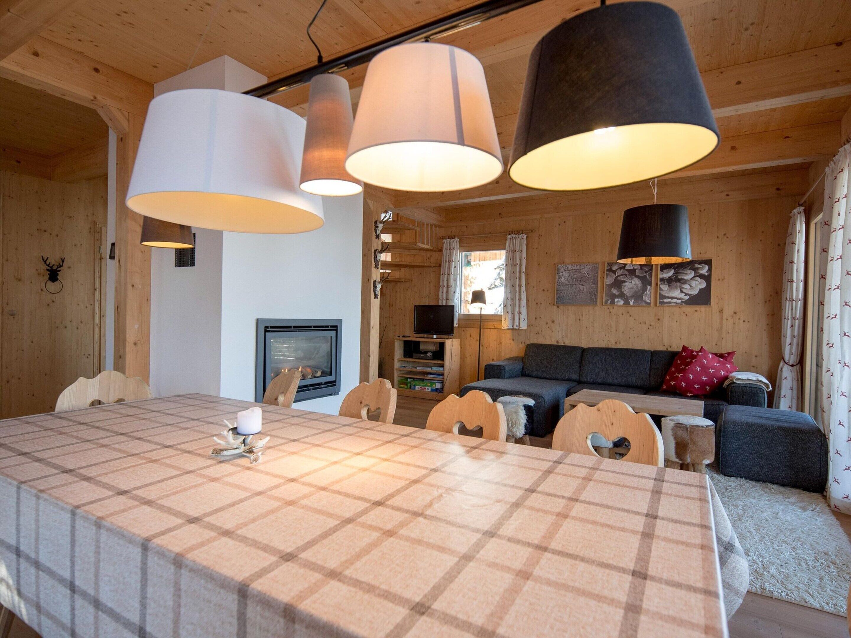 Un interior acogedor de cabaña con una mesa de comedor, sillas, un sofá y una chimenea.