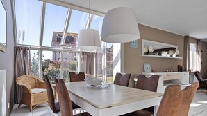 A dining area with a table, chairs, and pendant lights. - Bungalow in Breskens Near Lighthouse & Beach (Breskens)