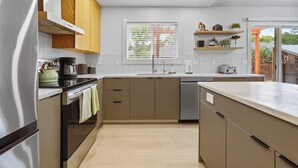 A modern kitchen with a central island, built-in oven, and a window with blinds. - Stunning 3BR Home-Backyard HOT TUB Oasis-Home Gym (Boise)