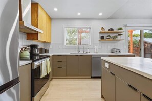 A modern kitchen with a central island, built-in oven, and a window with blinds. - Stunning 3BR Home-Backyard HOT TUB Oasis-Home Gym (Boise)
