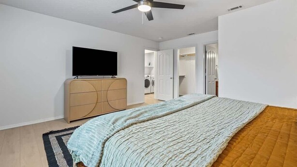 A bedroom with a bed, a ceiling fan, a TV, a wardrobe, and a washing machine in the background. - Stunning 3BR Home-Backyard HOT TUB Oasis-Home Gym (Boise)
